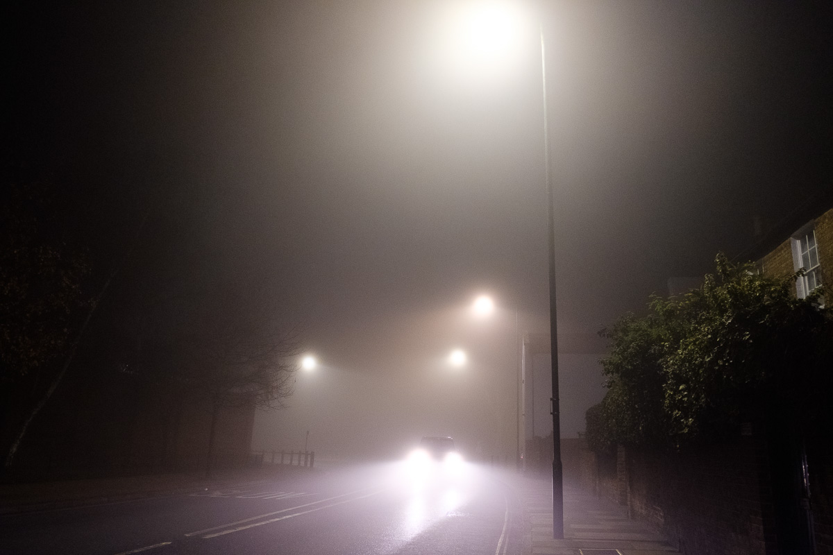 Car on a street in the fog at night