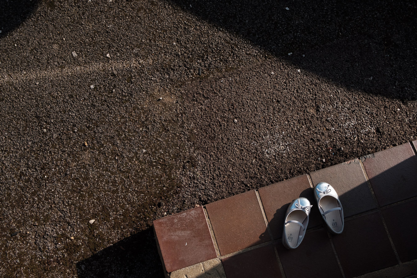 Detail photo showing girl's shoes taken off and left by the front door outside