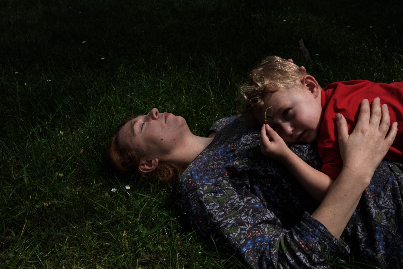 Mother and child resting together in a beautiful moment together in a grassy field.