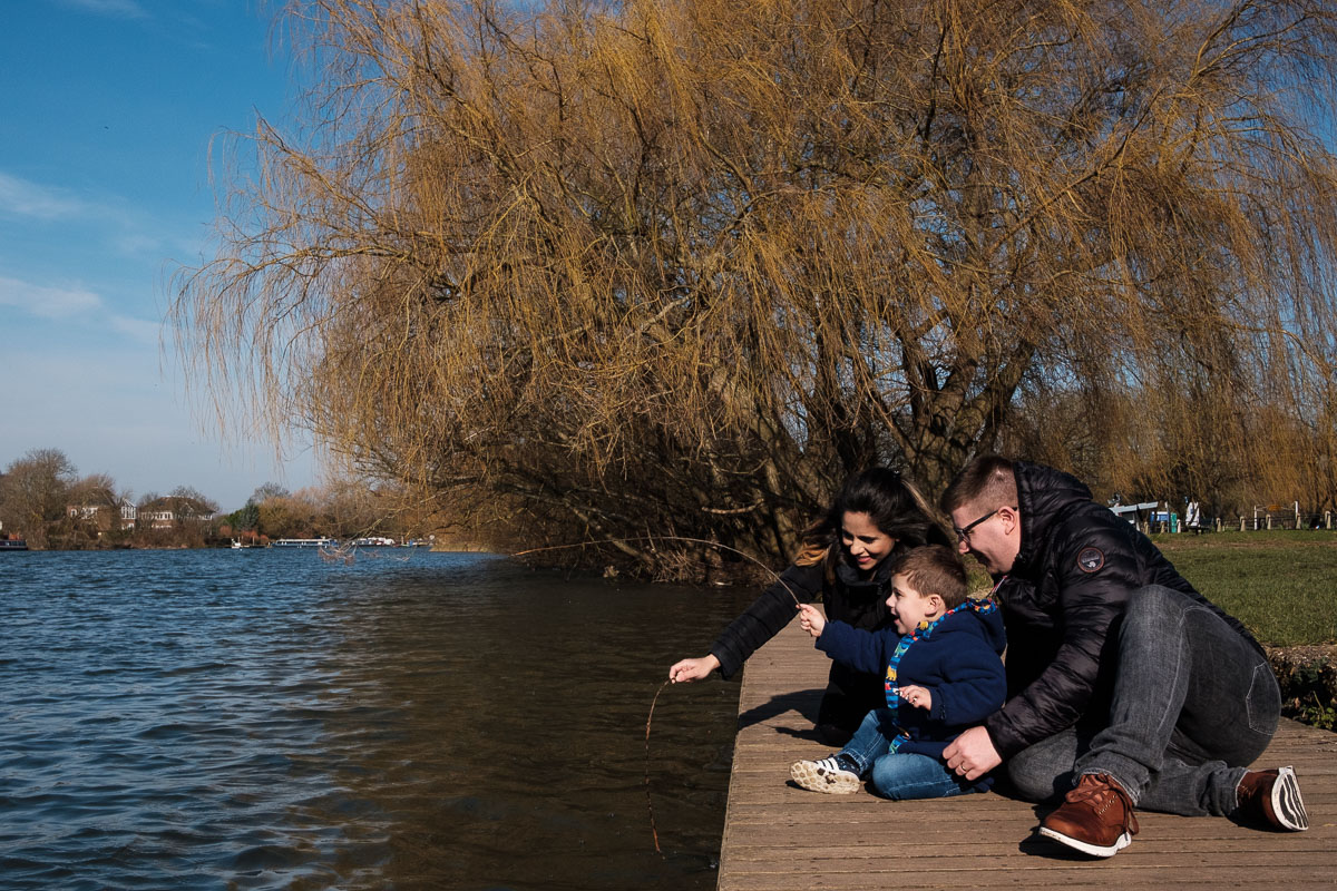 Family sitting on a jetty by the river Thames