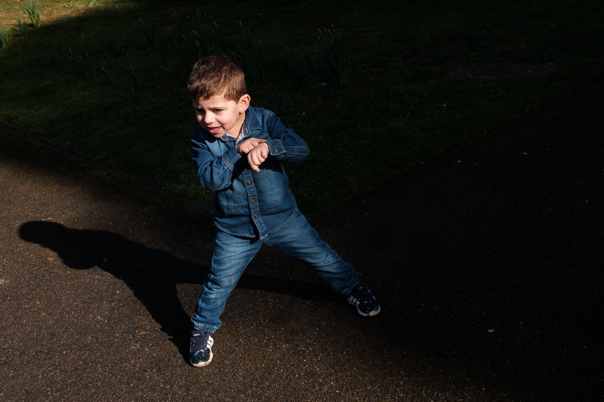 Boy play dancing in a patch of light outside