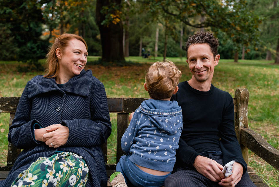 London family photographer Ben Heasman sitting on bench with wife and son.