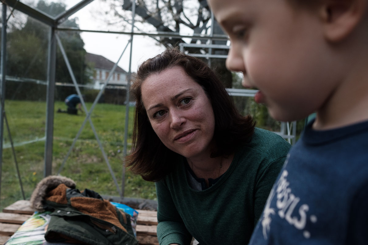Mother looks lovingly at child in garden greenhouse