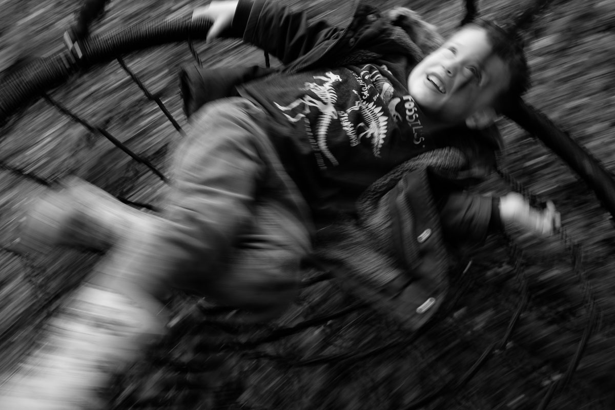 boy laughing whilst spinning on circular swing.