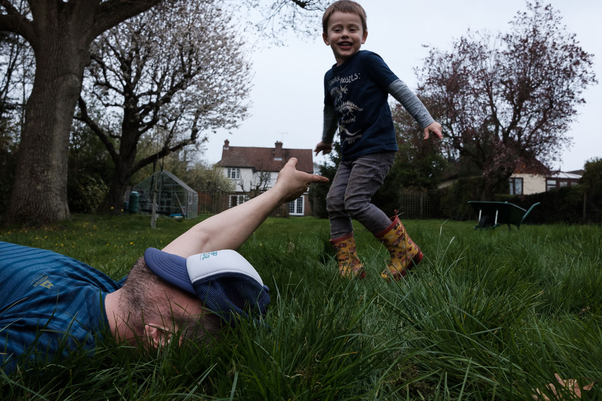 Dad pointing at son who is laughing in the garden.