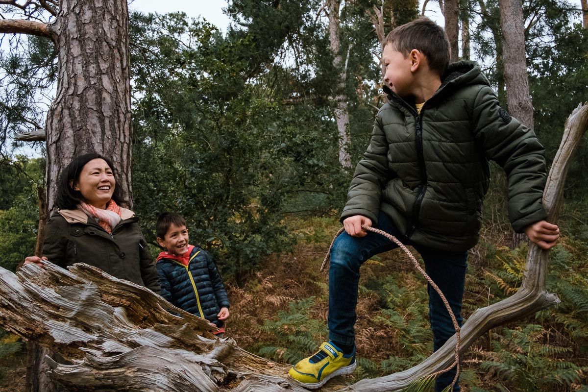Boy looking at mother and brother laughing in forest