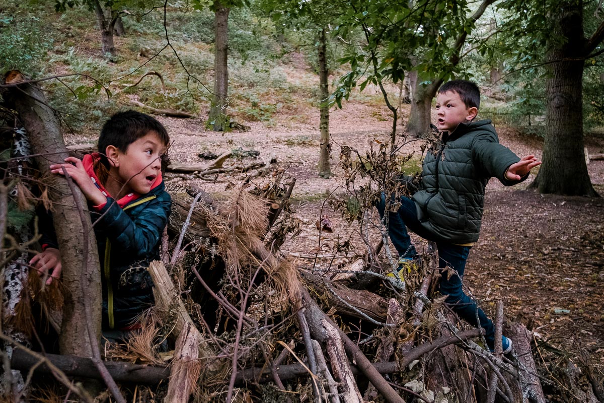 Two boys play in forest den.