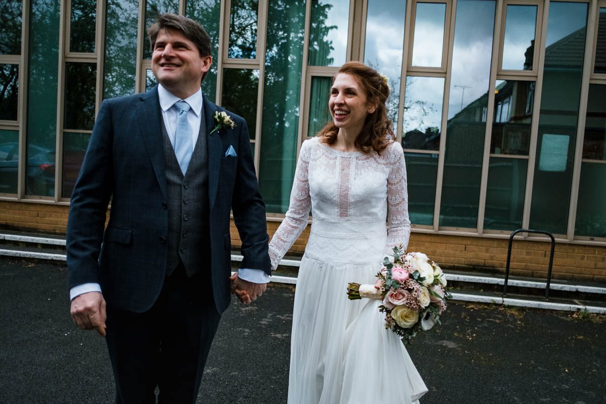 Bride and groom hold hands smiling outside church