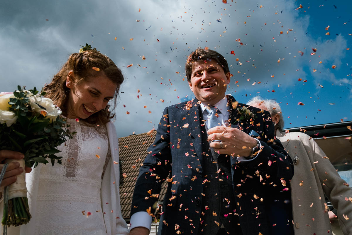 Confetti showering groom and bride outside church